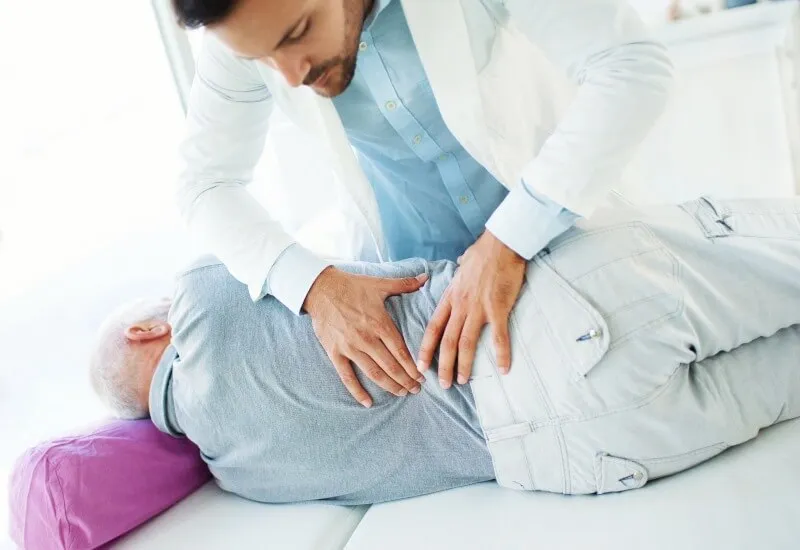 A doctor gives a back massage to a man in a chiropractic clinic in Boston, MA.